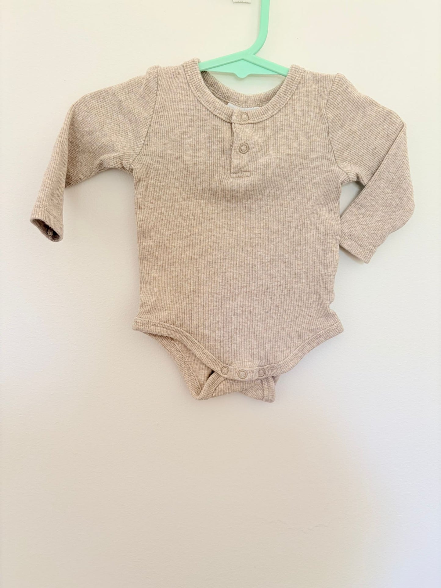 00 Milky light oatmeal ribbed long sleeve bodysuit.